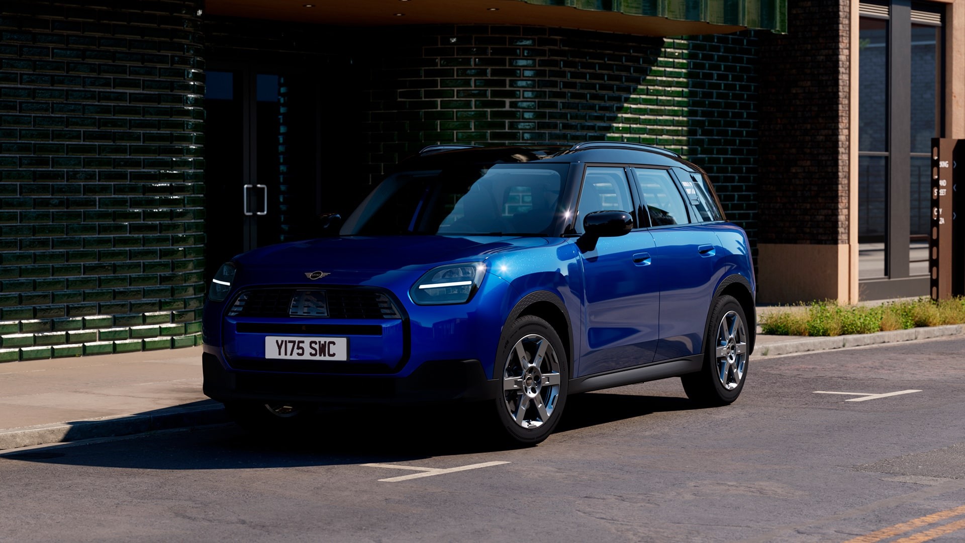 A blue MINI Countryman is parked outside a building, highlighting its stylish appearance and urban setting.